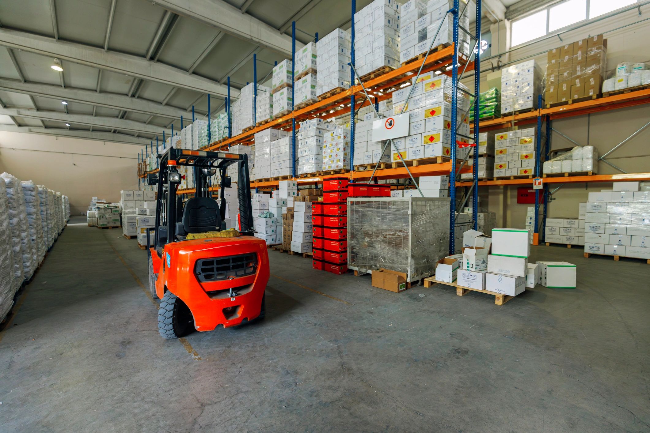 Forklift operating in a modern warehouse aisle with organized pallets